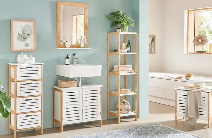 Badezimmer mit Möbeln mit weißen Lamellenfronten und hellem Holzgestell: Schubladenkommode, Waschbeckenunterschrank, Spiegel, Standregal, Wäschetruhe