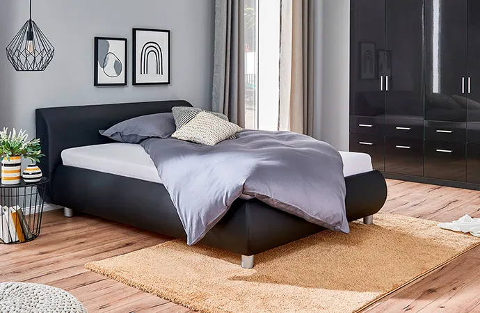 Schwarzes Polsterbett und schwarzer Kleiderschrank in Schlafzimmerszene