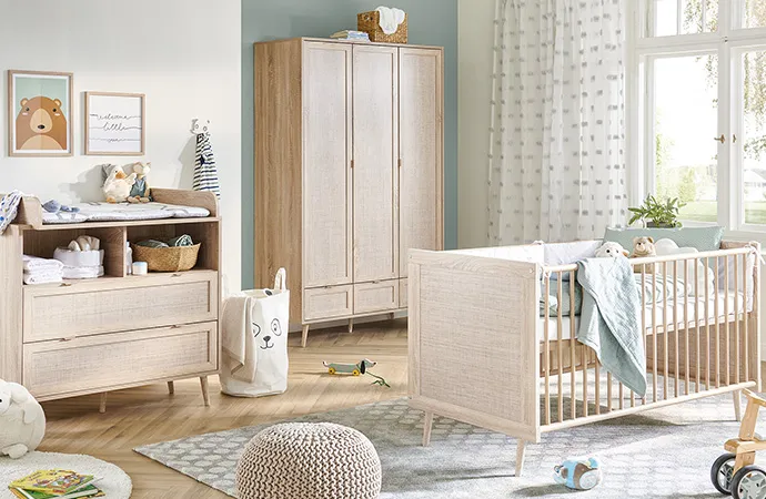 Babyzimmer in Holz- und Rattanoptik im Skandi-Stil, bestehend aus Wickelkommode, Schrank und Bett, Spielzeug, Babytextilien und Deko.