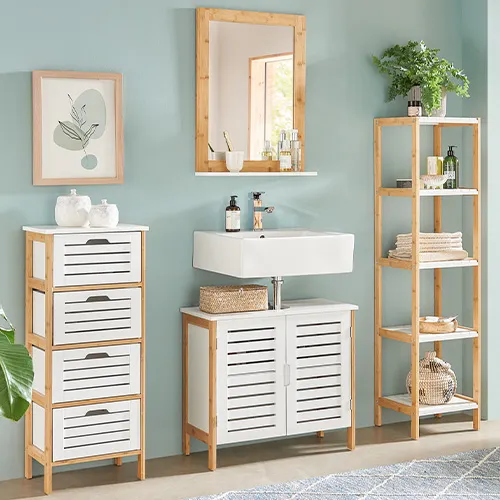 Badezimmer mit Möbeln mit weißen Lamellenfronten und hellem Holzgestell: Schubladenkommode, Waschbeckenunterschrank, Spiegel, Standregal, Wäschetruhe
