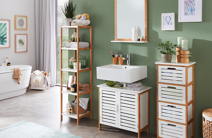 Badzimmer mit Badmöbeln (Regal, Spiegel mit Ablage, Waschbeckenunterschrank, Hochschrank) in Weiß und aus Holz vor grüner Wand