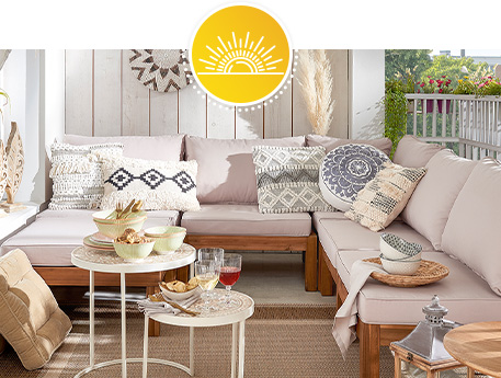 Terrasse mit Outdoorlounge aus Holz mit cremefarbigen Auflagen, Couchtischen, Rattanleuchte, Kissen, Geschirr und Deko im Boho-Stil