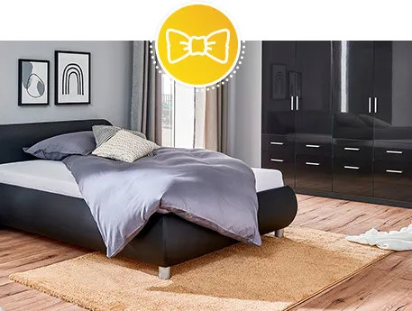 Schlafzimmer mit schwarzem Polsterbett und schwarzem Kleiderschrank